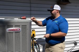 HVAC technician in blue Southern Air polo shirt inspecting a Lennox Elite air conditioning unit with tools nearby.
