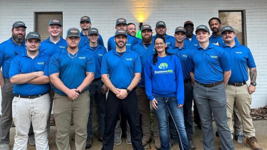 Team of HVAC, plumbing, and electrical professionals in blue Southern Air uniforms posing together indoors.